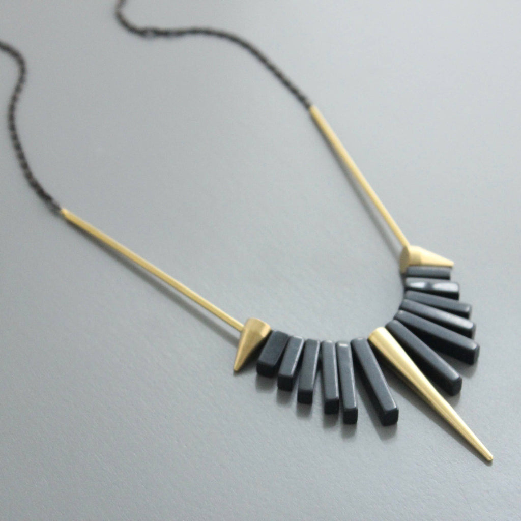 Collar corto de David Aubrey con piedras de ágata negra y detalles de latón dorado. Diseño artesanal exclusivo con extensor. Disponible en Ivoluxt.