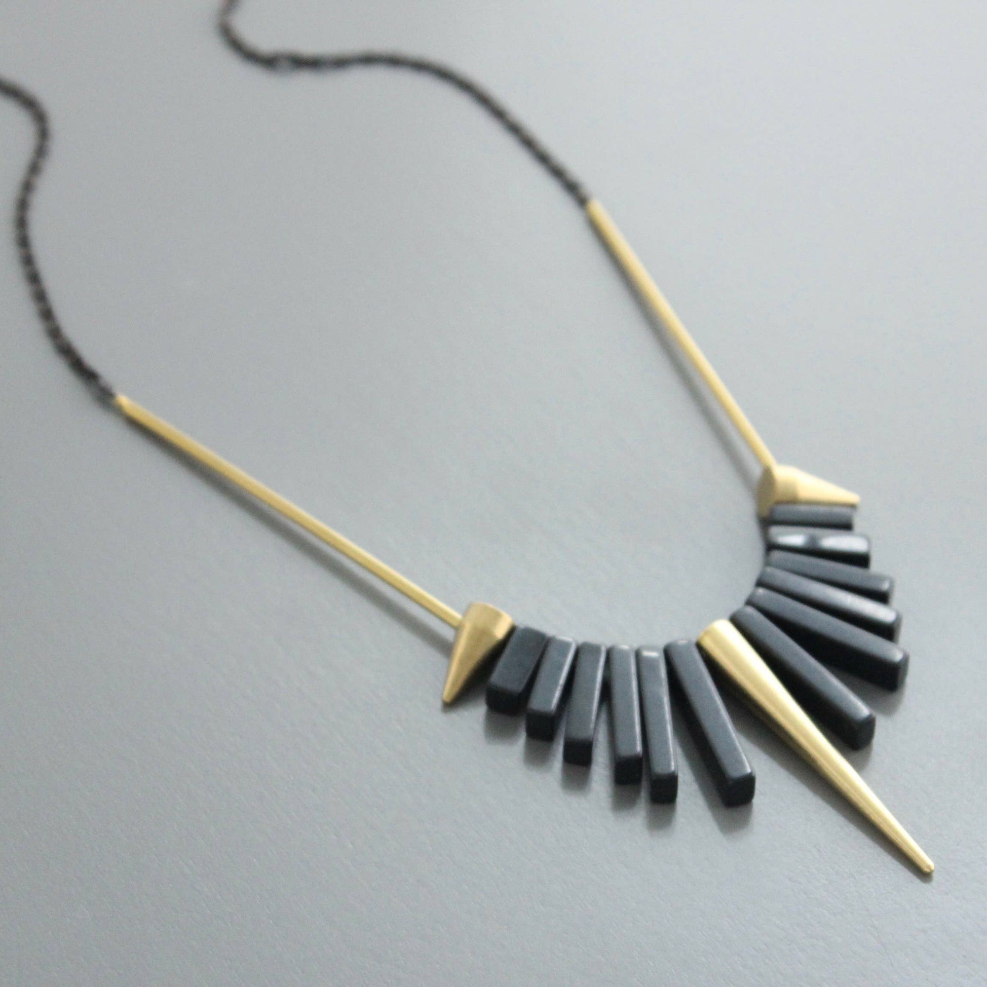 Collar corto de David Aubrey con piedras de ágata negra y detalles de latón dorado. Diseño artesanal exclusivo con extensor. Disponible en Ivoluxt.