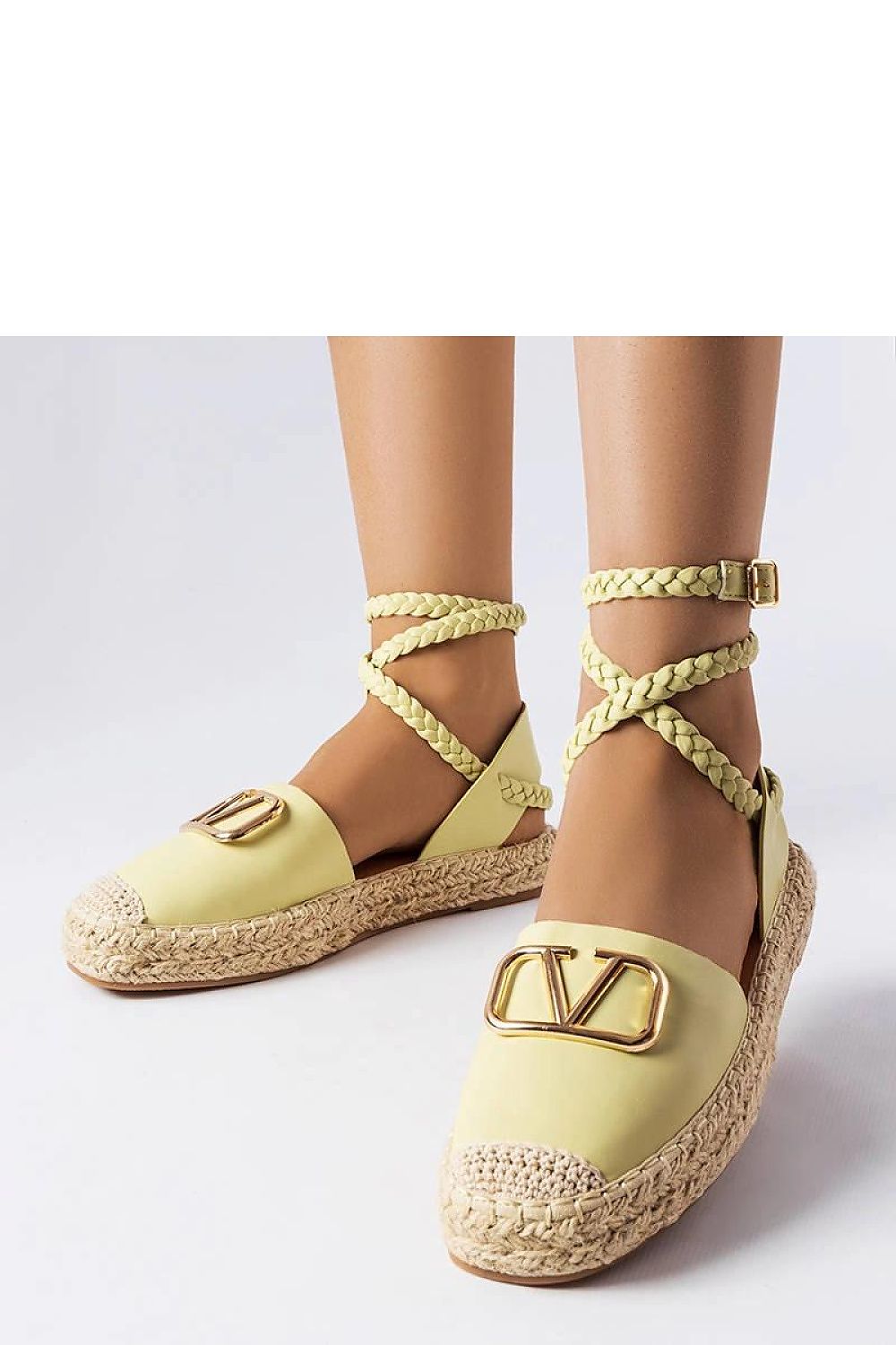 Mujer con alpargatas beige de eco cuero con lazada al tobillo y detalle metálico dorado, sobre fondo blanco.