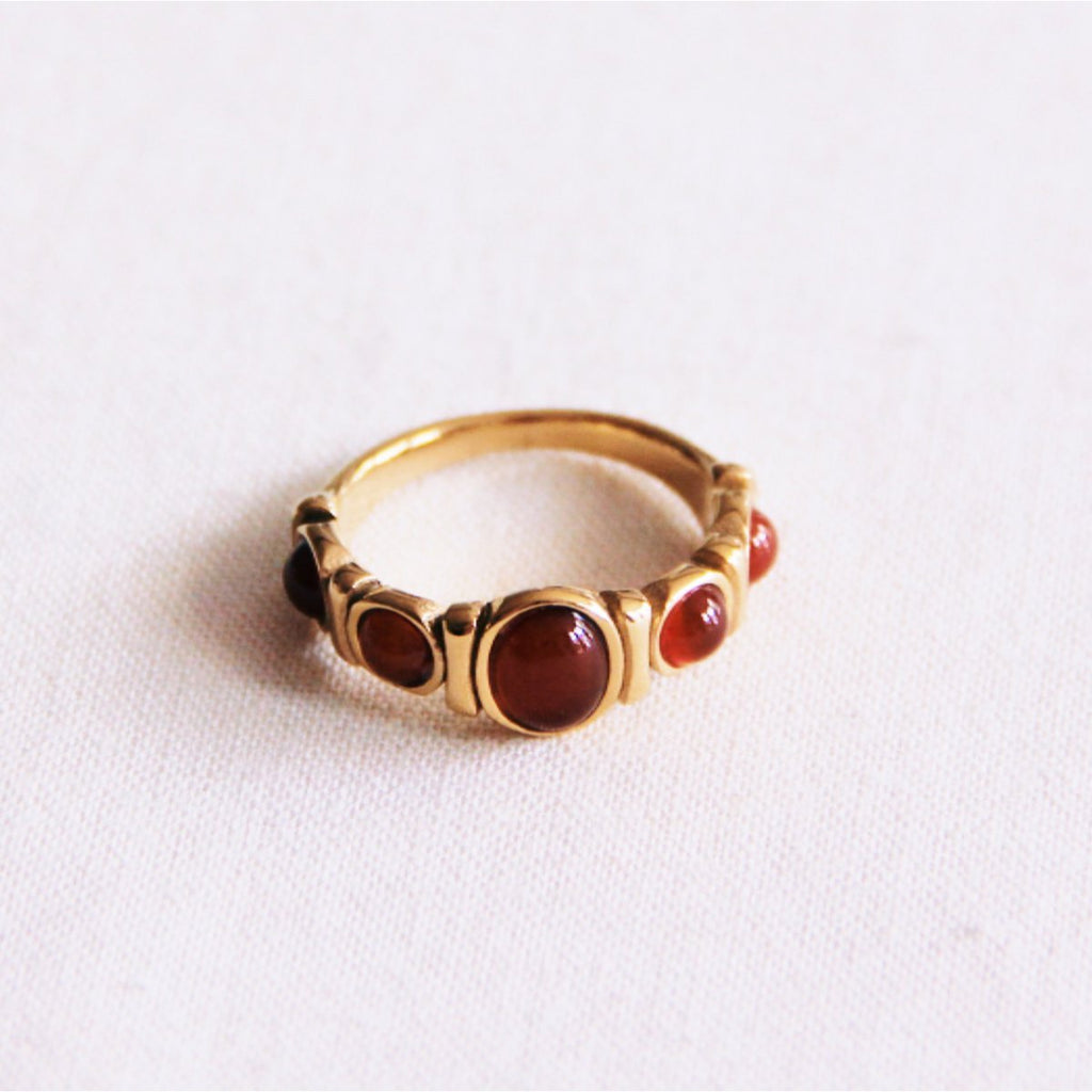 Anillo de acero inoxidable dorado con cinco piedras redondas de color rojo intenso engarzadas en fila