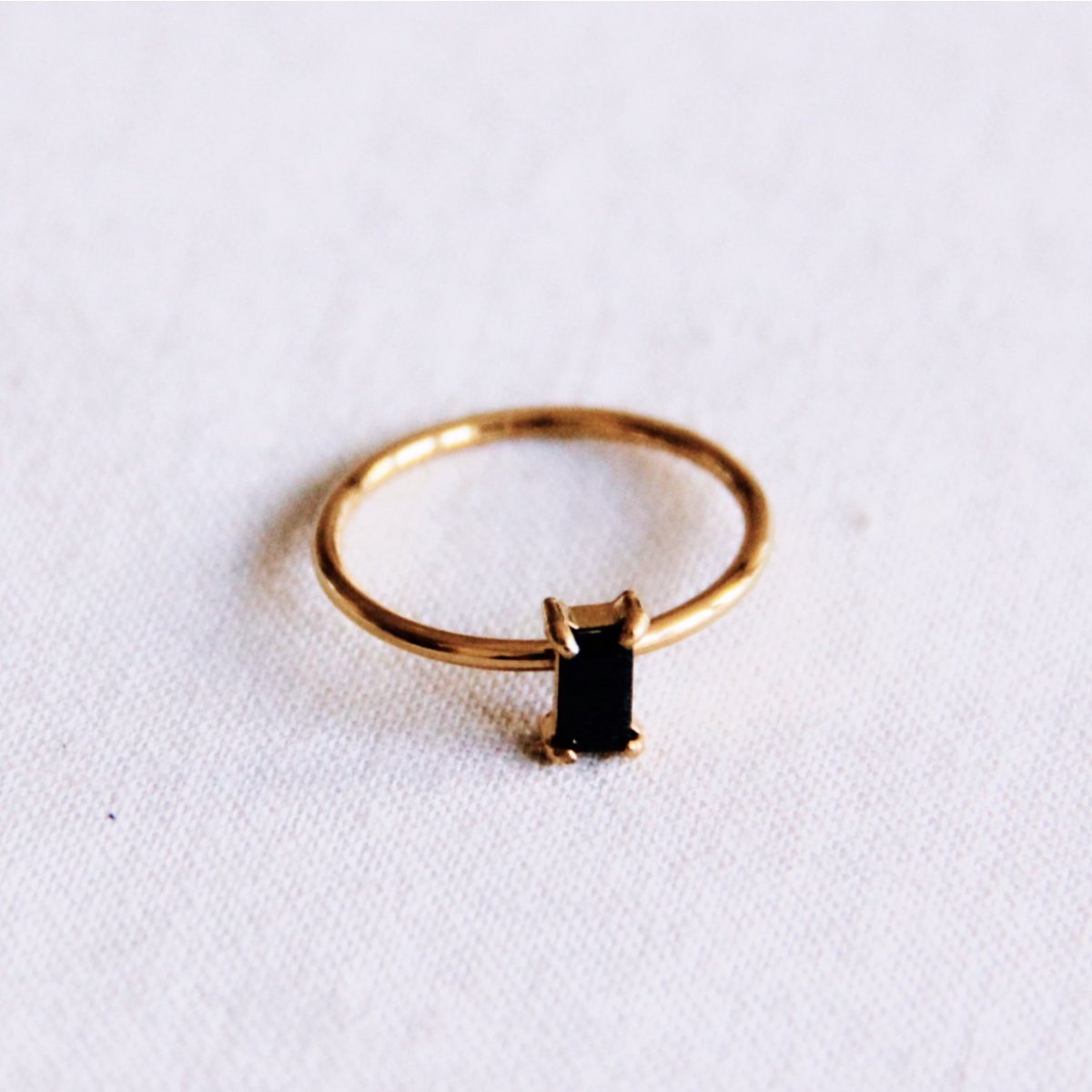 Anillo minimalista de acero inoxidable dorado con una pequeña piedra negra rectangular engarzada