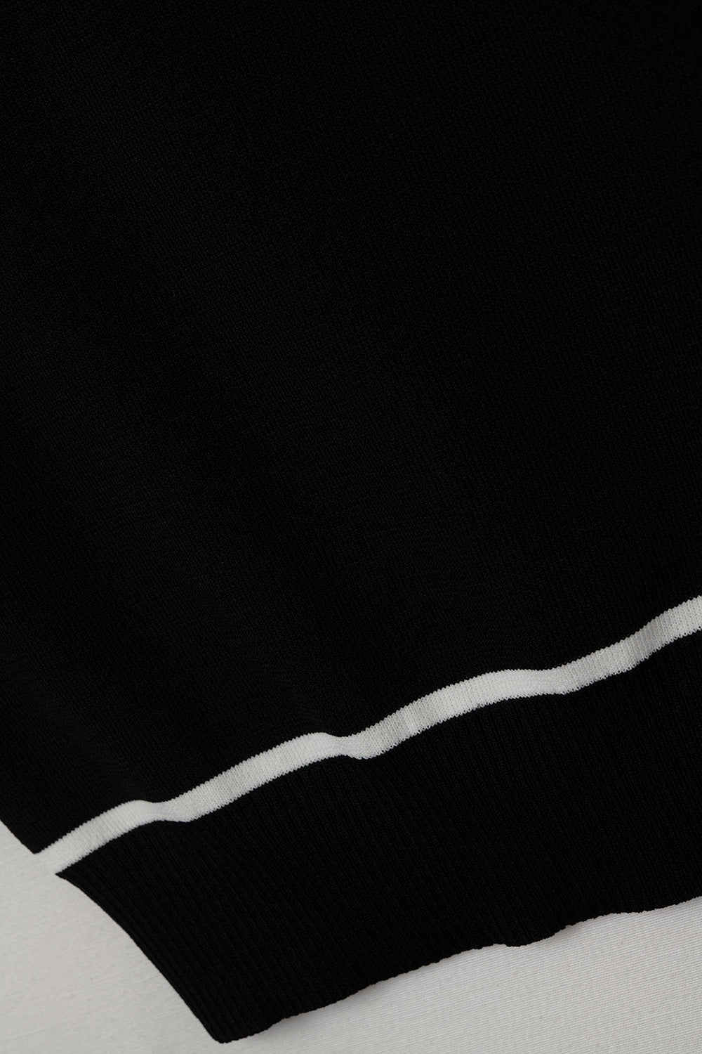 Top halter negro de punto fino con detalles blancos en contraste.