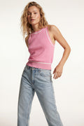 Top halter rosa empolvado de punto fino con detalles blancos combinado con vaqueros claros de tiro alto.