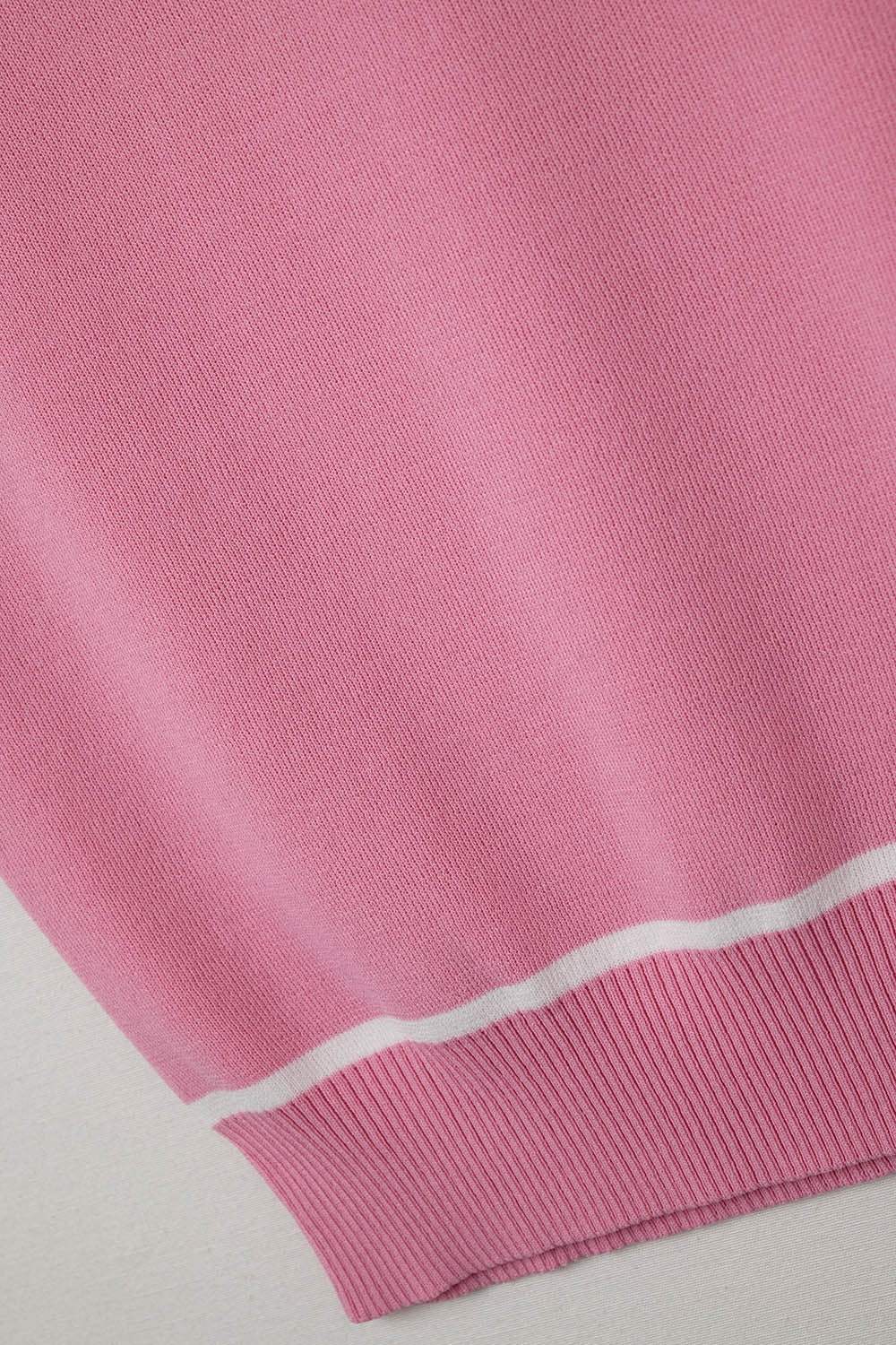 Top halter rosa empolvado de punto fino con detalles blancos.