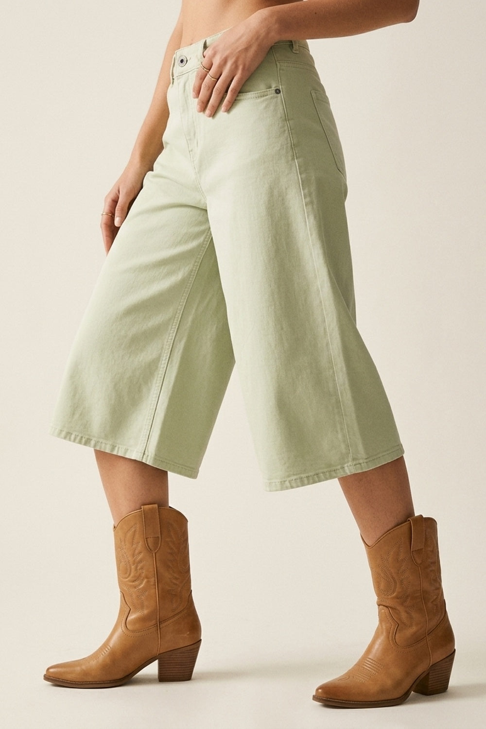 bermudas vaqueras tipo culotte en color verde menta de tiro alto, combinadas con top de tirantes blanco y botas cowboy color camel.