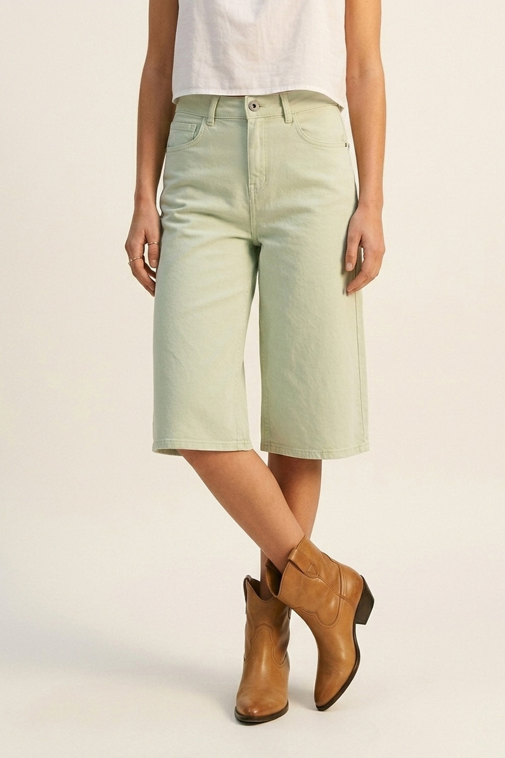 bermudas vaqueras tipo culotte en color verde menta de tiro alto, combinadas con top de tirantes blanco y botas cowboy color camel.