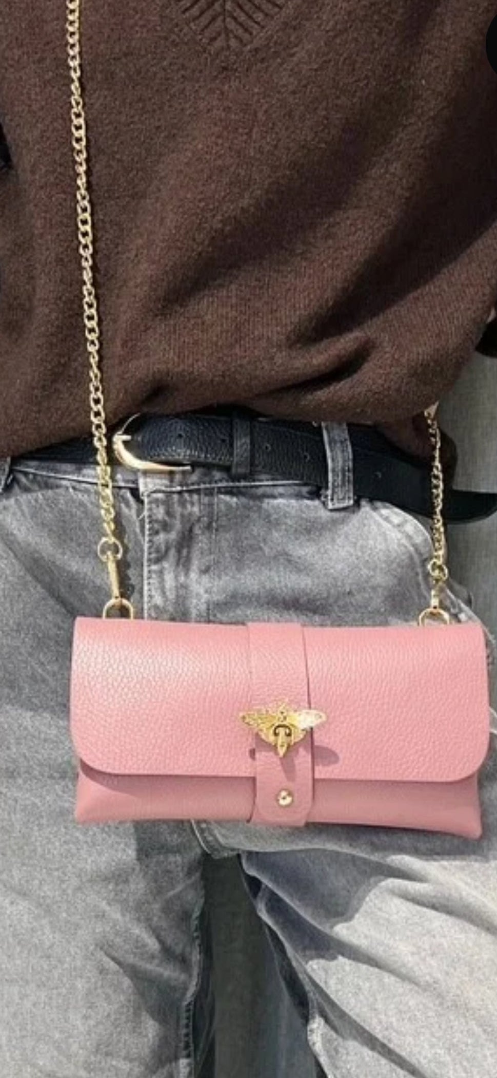 Bolso de mano tipo sobre en piel granulada rosa pastel con cierre de abeja dorada y cadena.