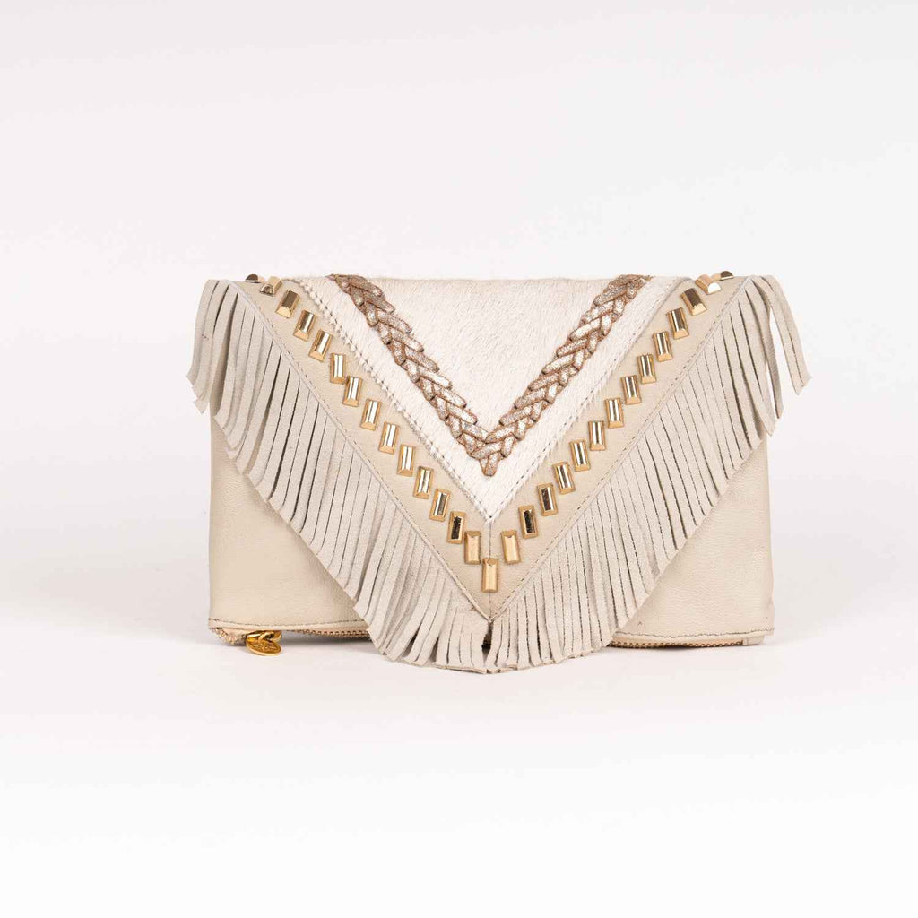 Bolso tipo clutch de estilo boho chic en piel de ante marfil, con solapa en forma de V, largos flecos, detalles trenzados metálicos y tachuelas doradas.