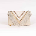 Bolso tipo clutch de estilo boho chic en piel de ante marfil, con solapa en forma de V, largos flecos, detalles trenzados metálicos y tachuelas doradas.