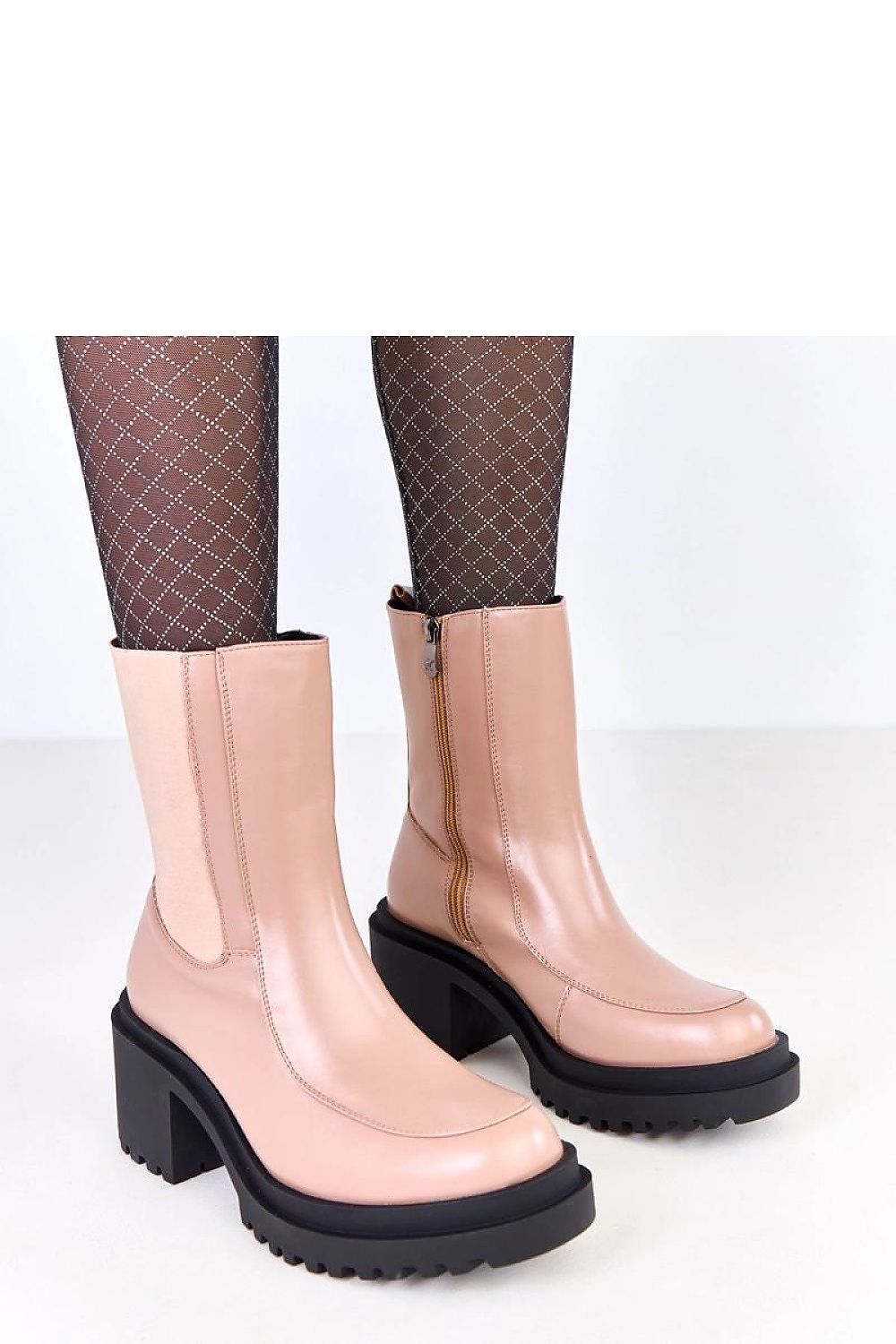 Botines beige con cremallera lateral y detalle de suela robusta dentada vistos desde ángulo superior.