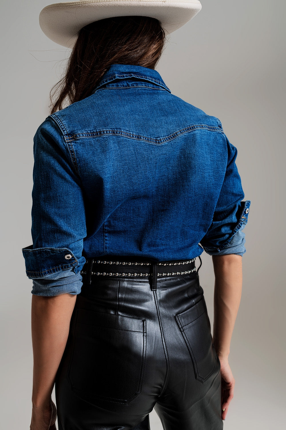 Vista trasera de una camisa vaquera de mujer con corte entallado en denim oscuro.