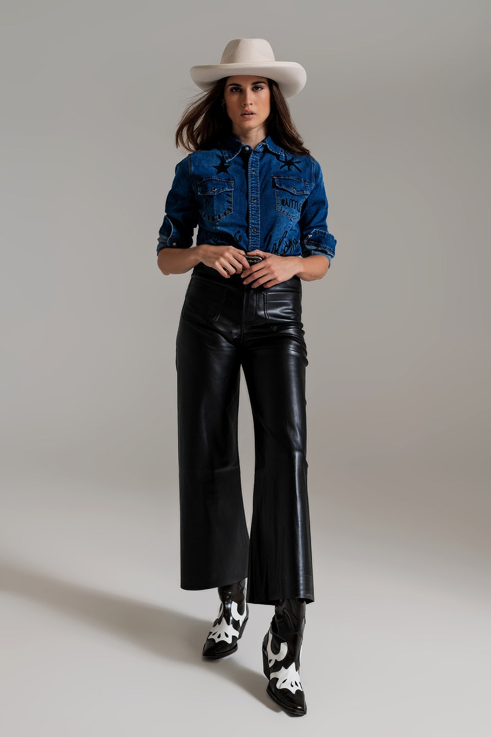 Look completo con camisa vaquera ajustada con strass y pantalones de cuero negro.