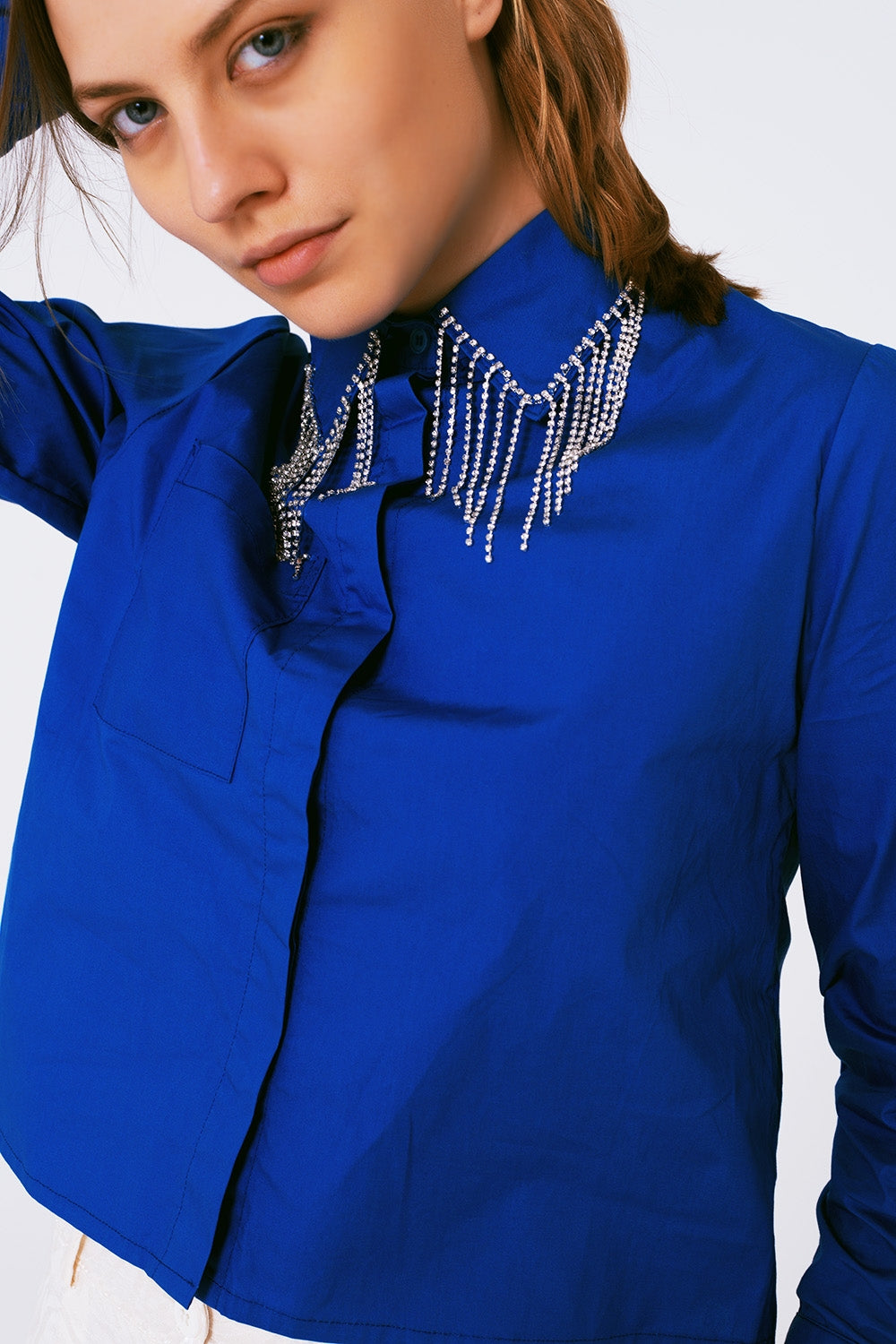 Camisa de algodón en color azul cobalto con flecos de strass colgando del cuello.