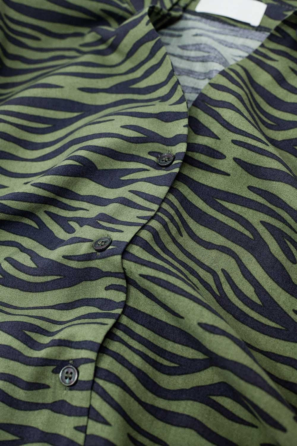 Detalle de botones y tejido ligero en blusa animal print verde