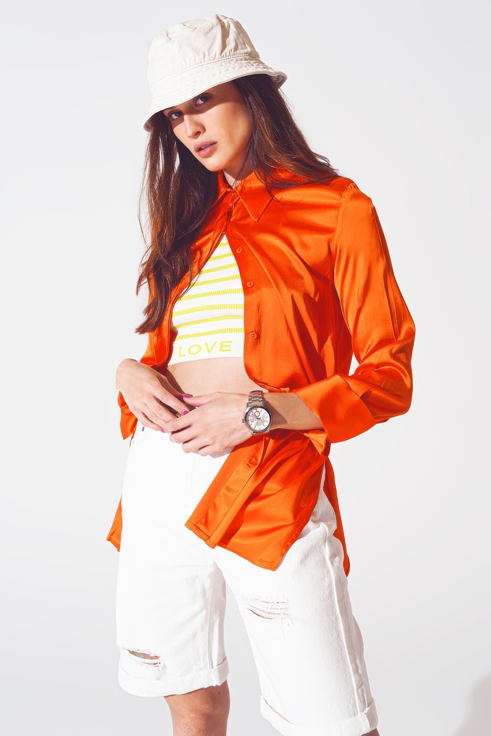 Primer plano de una camisa de satén en color naranja vibrante, mostrando el brillo del tejido.