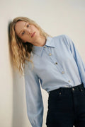 Camisa fluida de lyocell color azul claro con puños anchos y botones joya variados con cristales y zafiro azul.