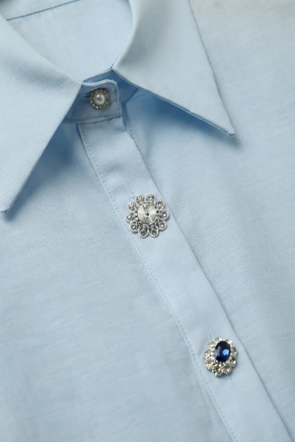 Camisa fluida de lyocell color azul claro con puños anchos y botones joya variados con cristales y zafiro azul.