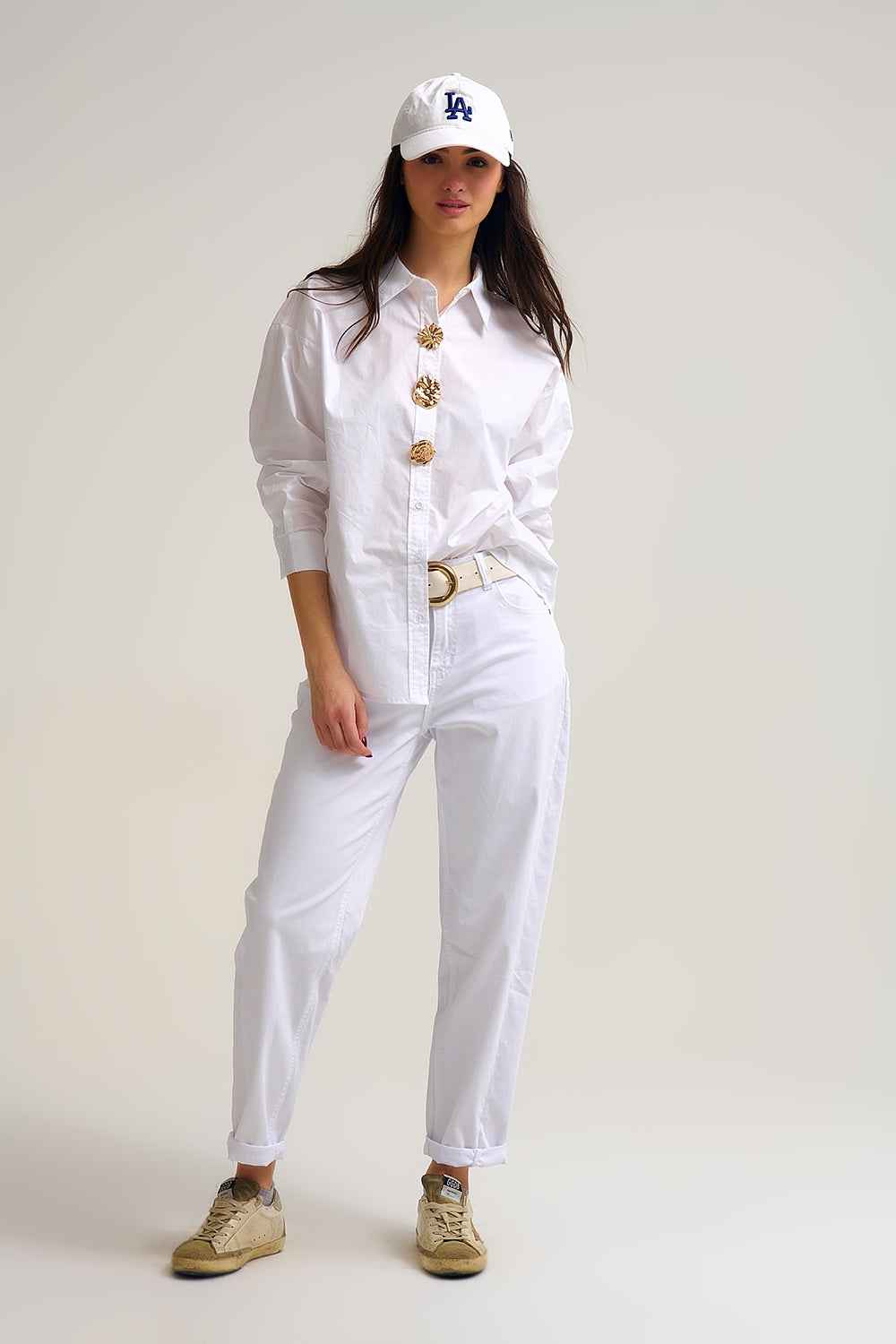 Mujer vistiendo camisa amplia de popelín blanco nieve 100% algodón con botones dorados grandes tipo joya.