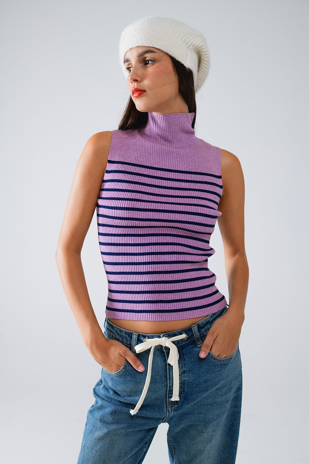 Modelo con top de punto sin mangas y cuello alto con un estampado de rayas horizontales en tonos lavanda y crudo.