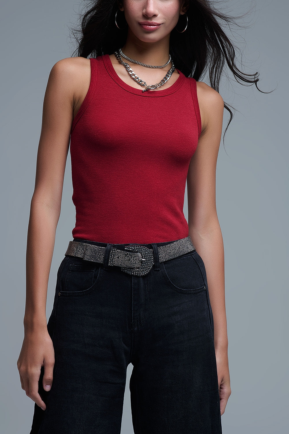Detalle de la camiseta roja ajustada y cinturón brillante