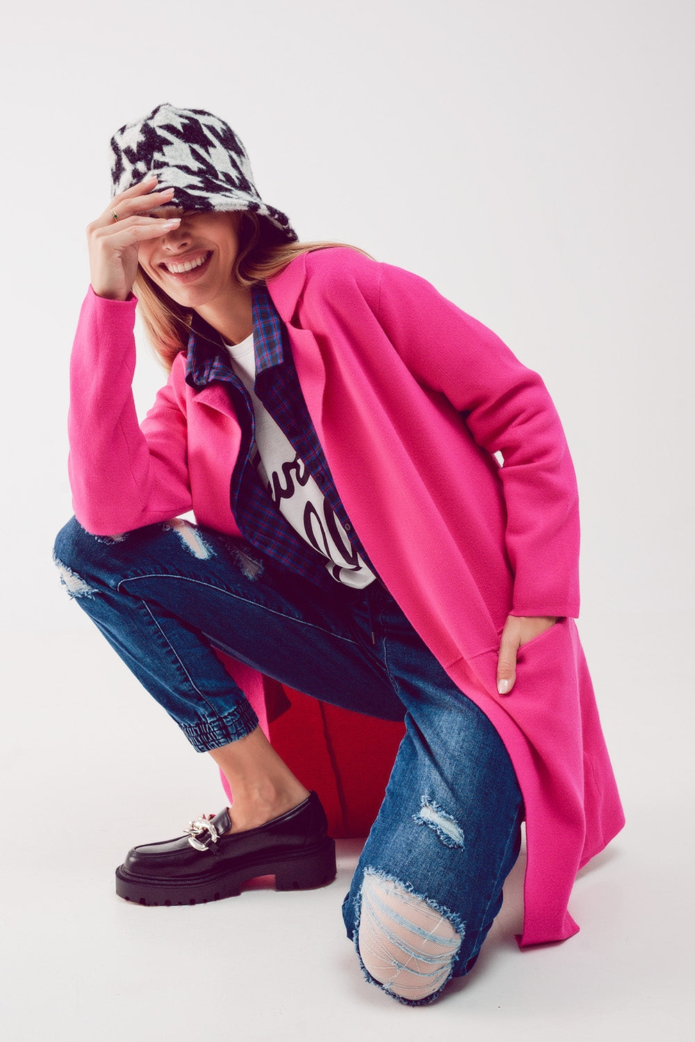 Mujer con estilo urbano vistiendo cárdigan abrigo oversize color fucsia con solapas sobre capas de ropa.