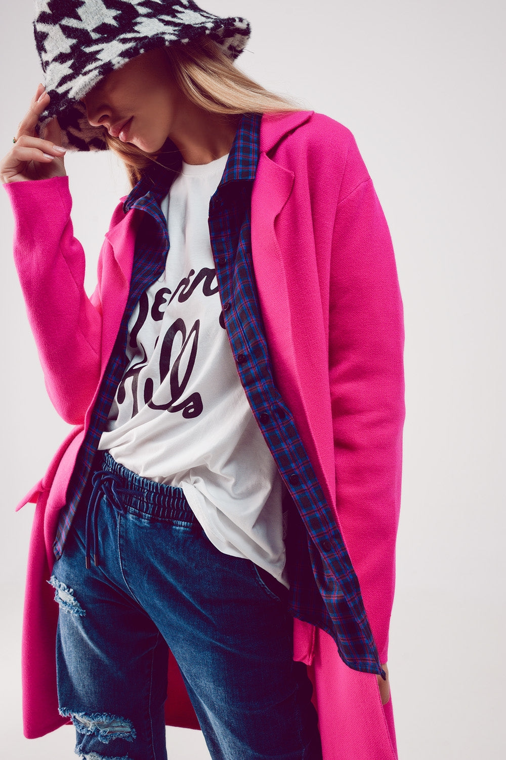 Mujer con estilo urbano vistiendo cárdigan abrigo oversize color fucsia con solapas sobre capas de ropa.