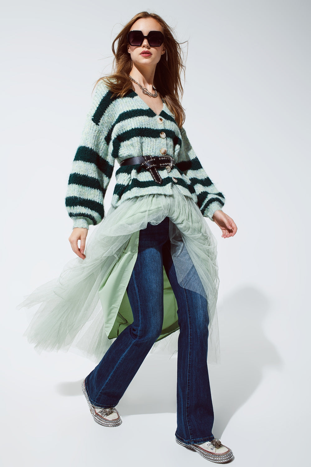 Look completo con cárdigan de punto a rayas verdes, ceñido con un cinturón, y falda midi satinada.