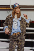 Mujer vistiendo chaqueta vaquera oversized con estampado de leopardo, estilo urbano con gorra y capas