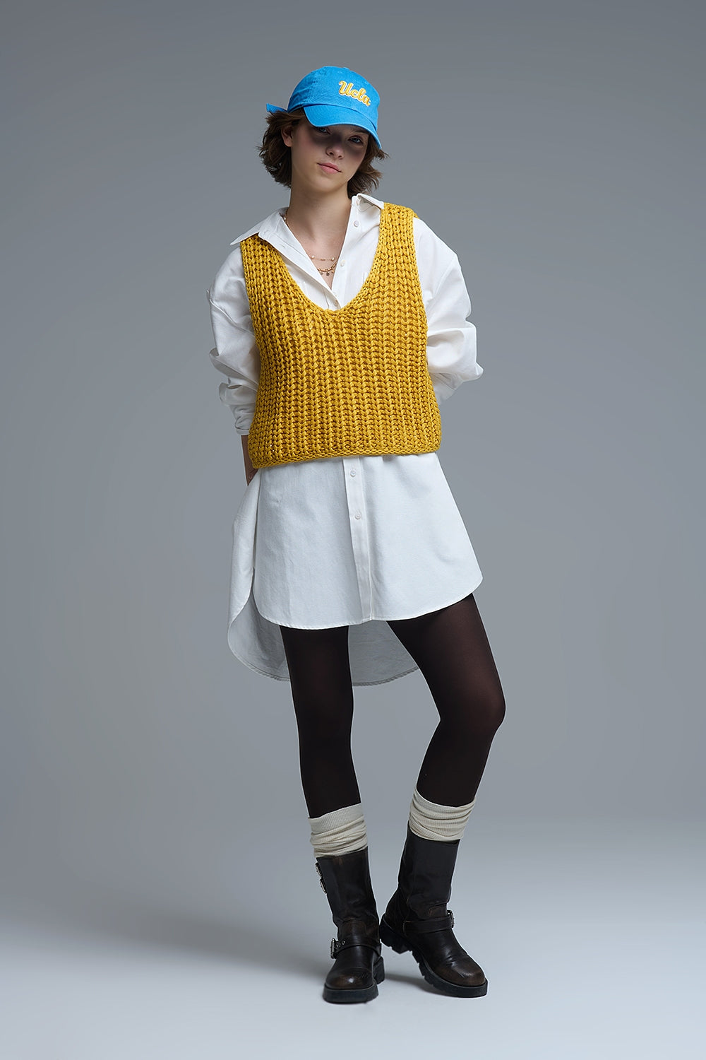 Chaleco mostaza combinado con camisa blanca y botas