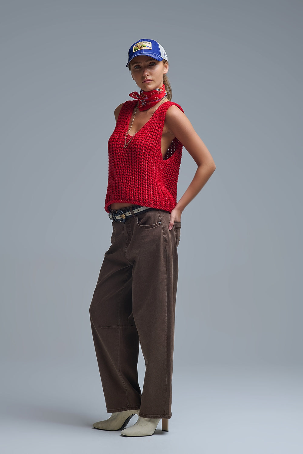 Look completo de mujer con chaleco de punto rojo oversize y pantalones baggy marrones, con botines beige.