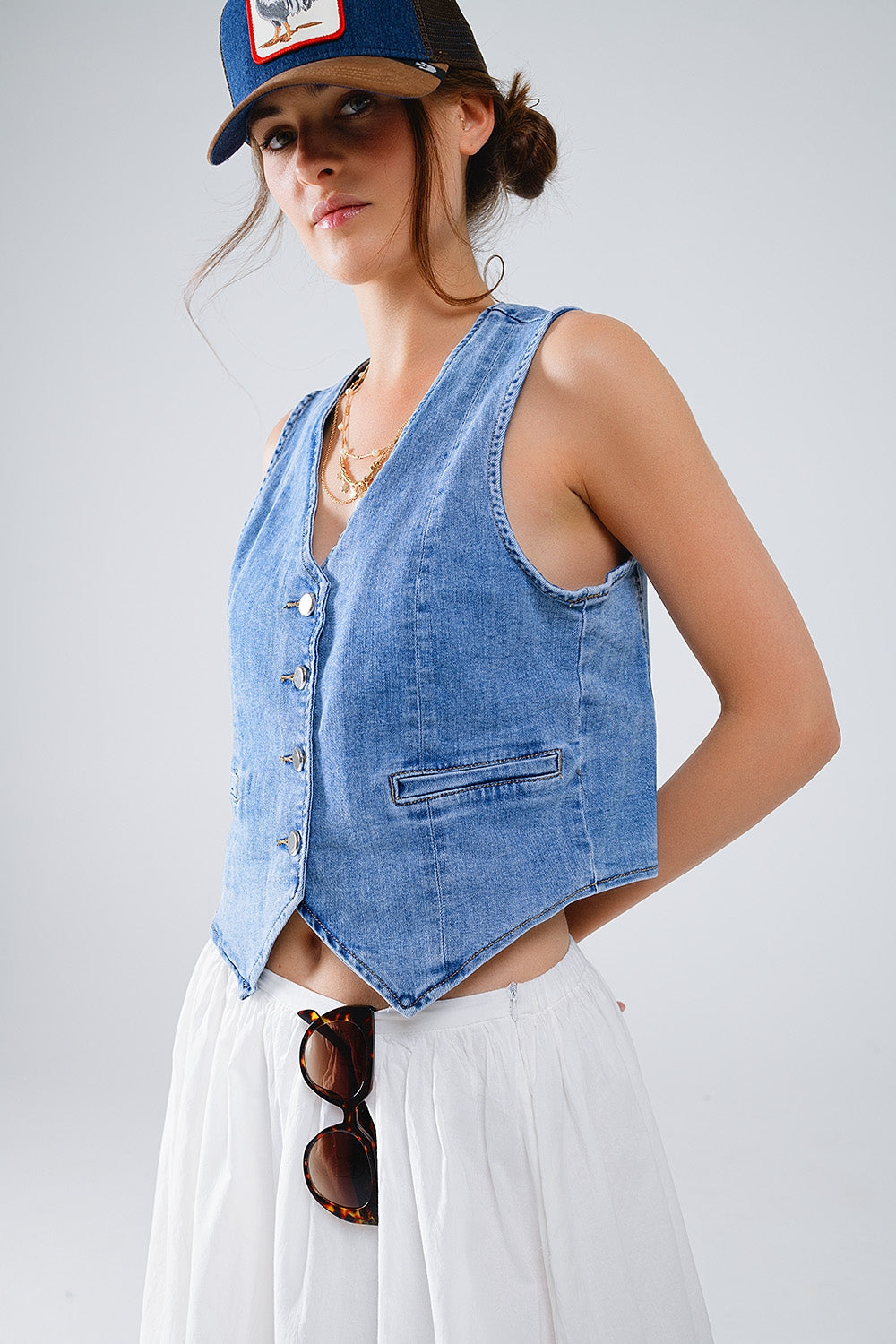 Vista lateral de chaleco denim azul lavado con corte femenino.