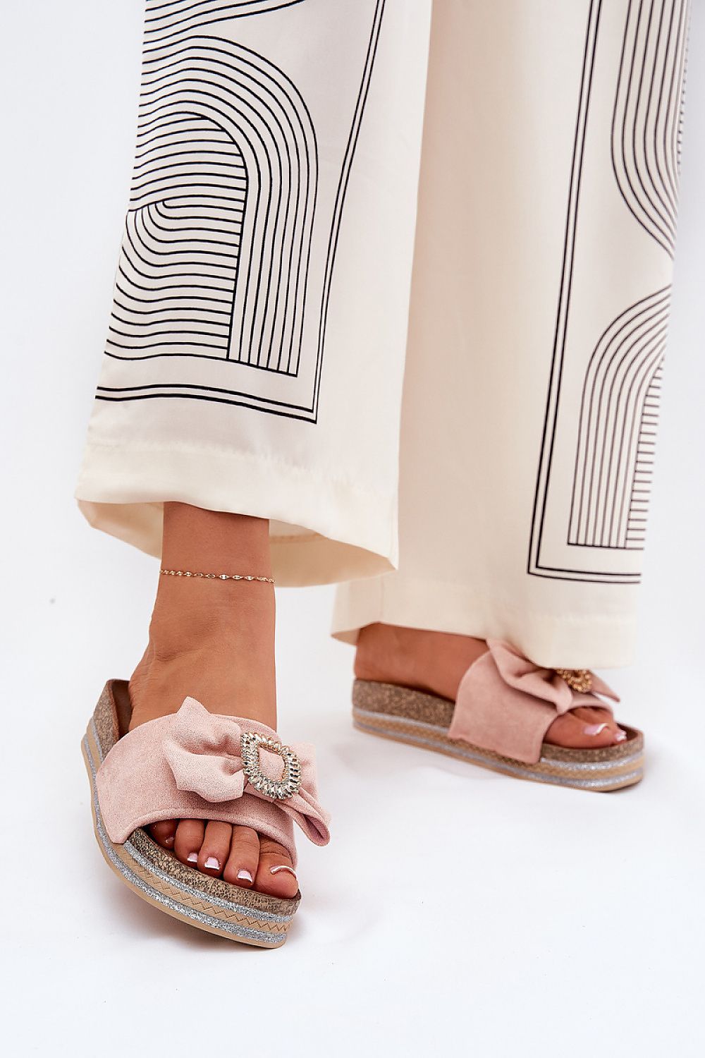 Mujer con chanclas rosas de plataforma con lazo y broche decorativo