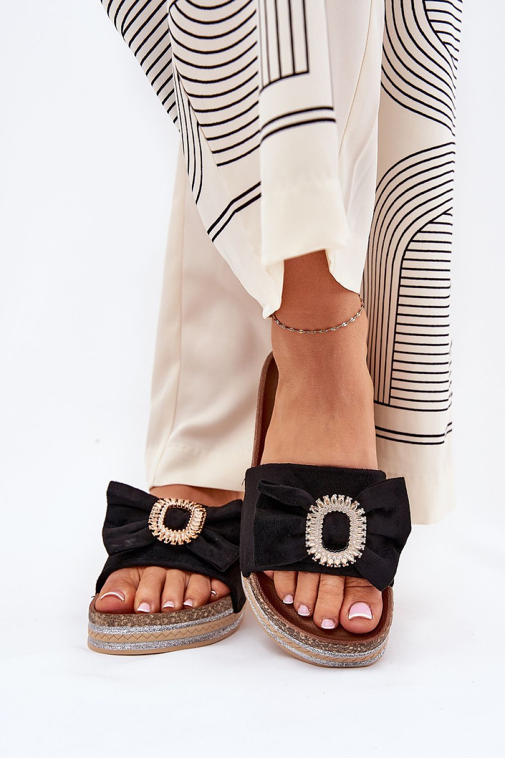  Mujer con chanclas negras de plataforma con lazo y broche decorativo