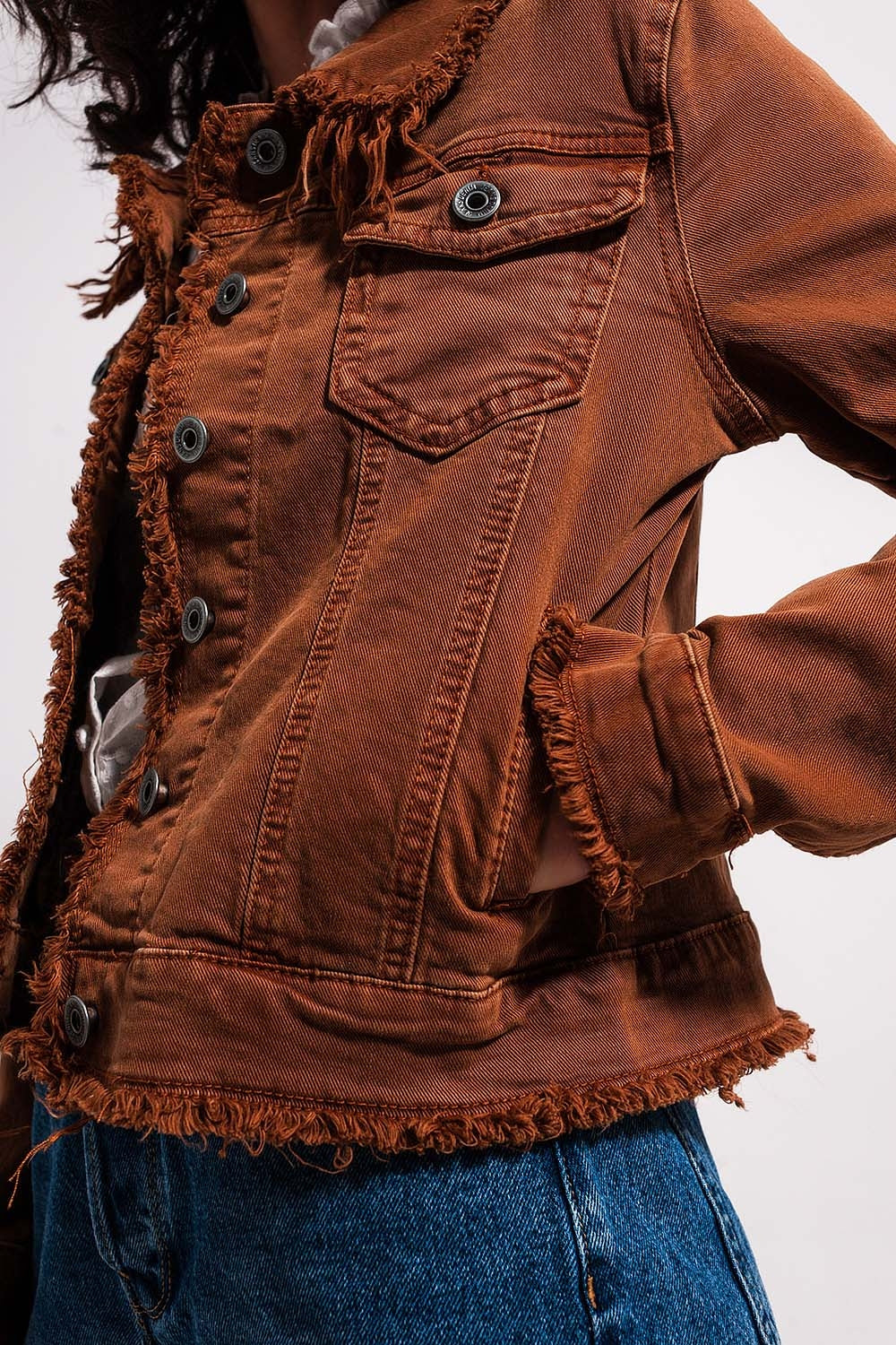 Vista lateral de chaqueta vaquera marrón con bolsillos.