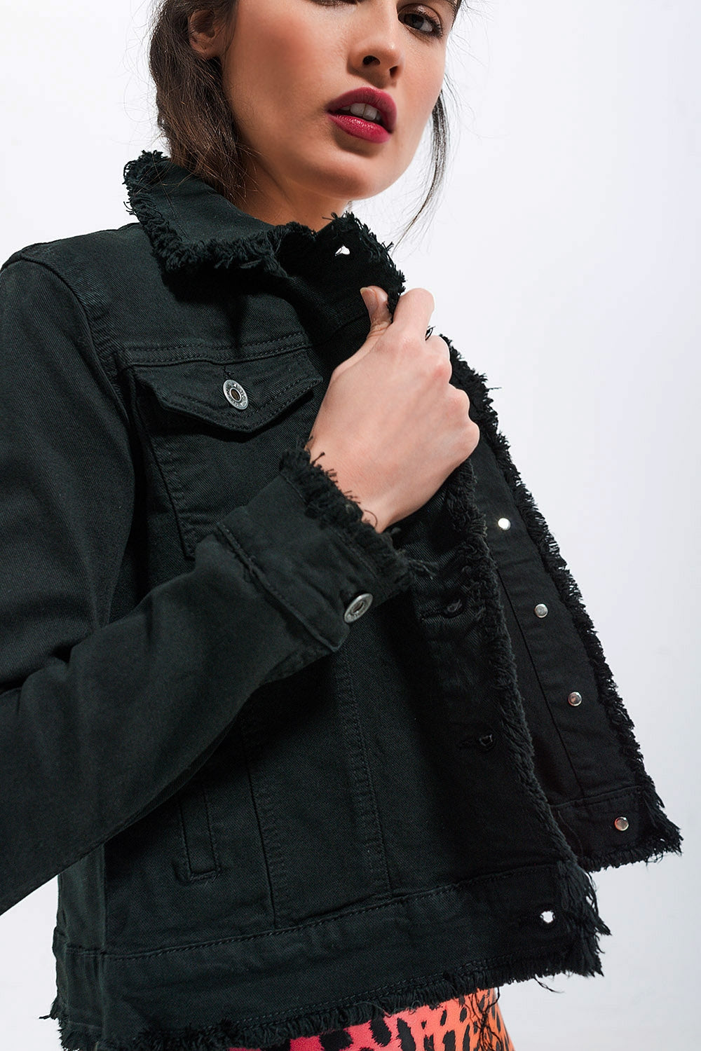 Detalle de botones metálicos en chaqueta vaquera negra.