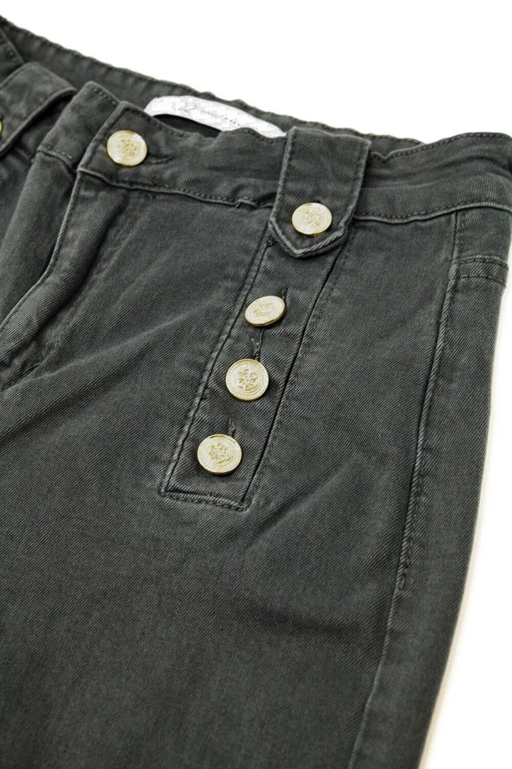 Primer plano de la doble botonadura dorada de un pantalón de talle alto estilo marinero.