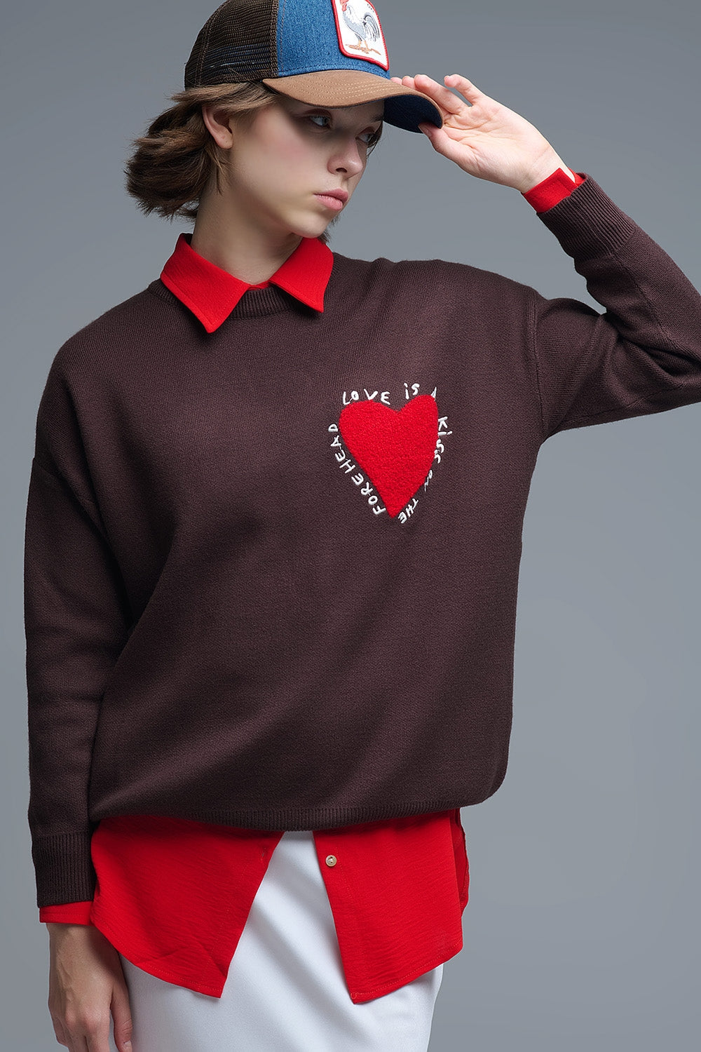 Primer plano de la textura de rizo de un corazón rojo bordado en un jersey de punto marrón.