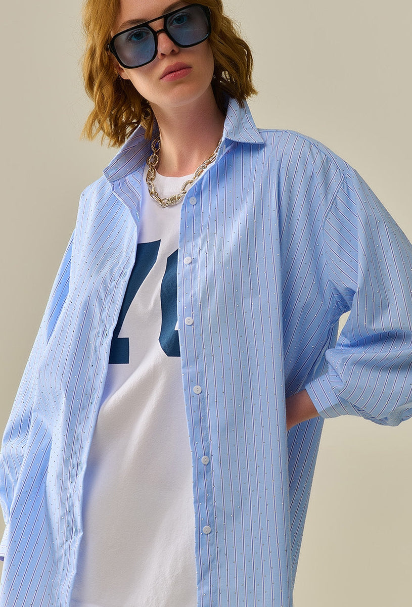 Primer plano del cuello y hombros de camisa azul a rayas con aplicaciones de cristales brillantes.