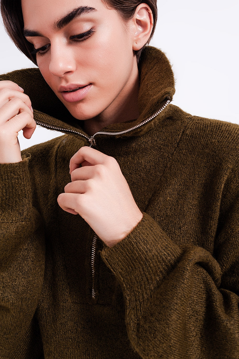 Primer plano del detalle de la cremallera metálica en el cuello alto de un vestido de punto verde.