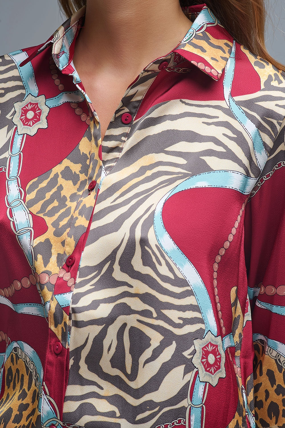 Primer plano del estampado de cadenas y animal print de una camisa de satén roja.