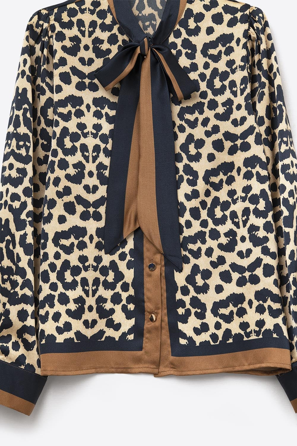 Detalle del lazo y la botonadura con color block de la blusa de satén de leopardo.