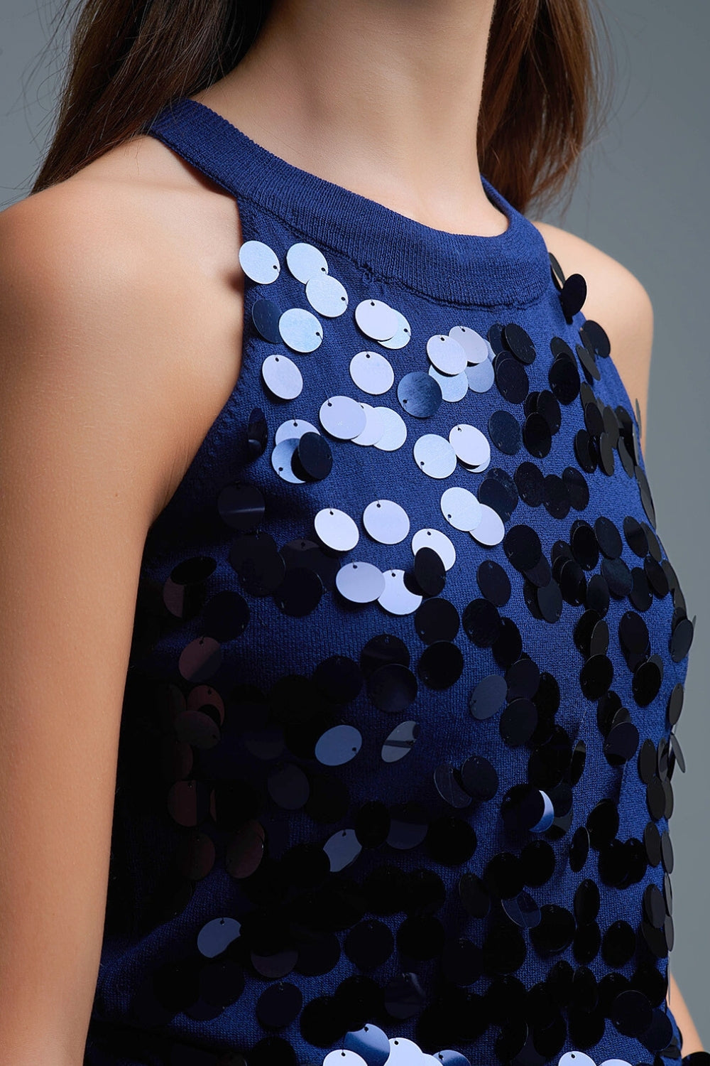 Primer plano de los discos de lentejuelas azules cosidos sobre top de punto fino.