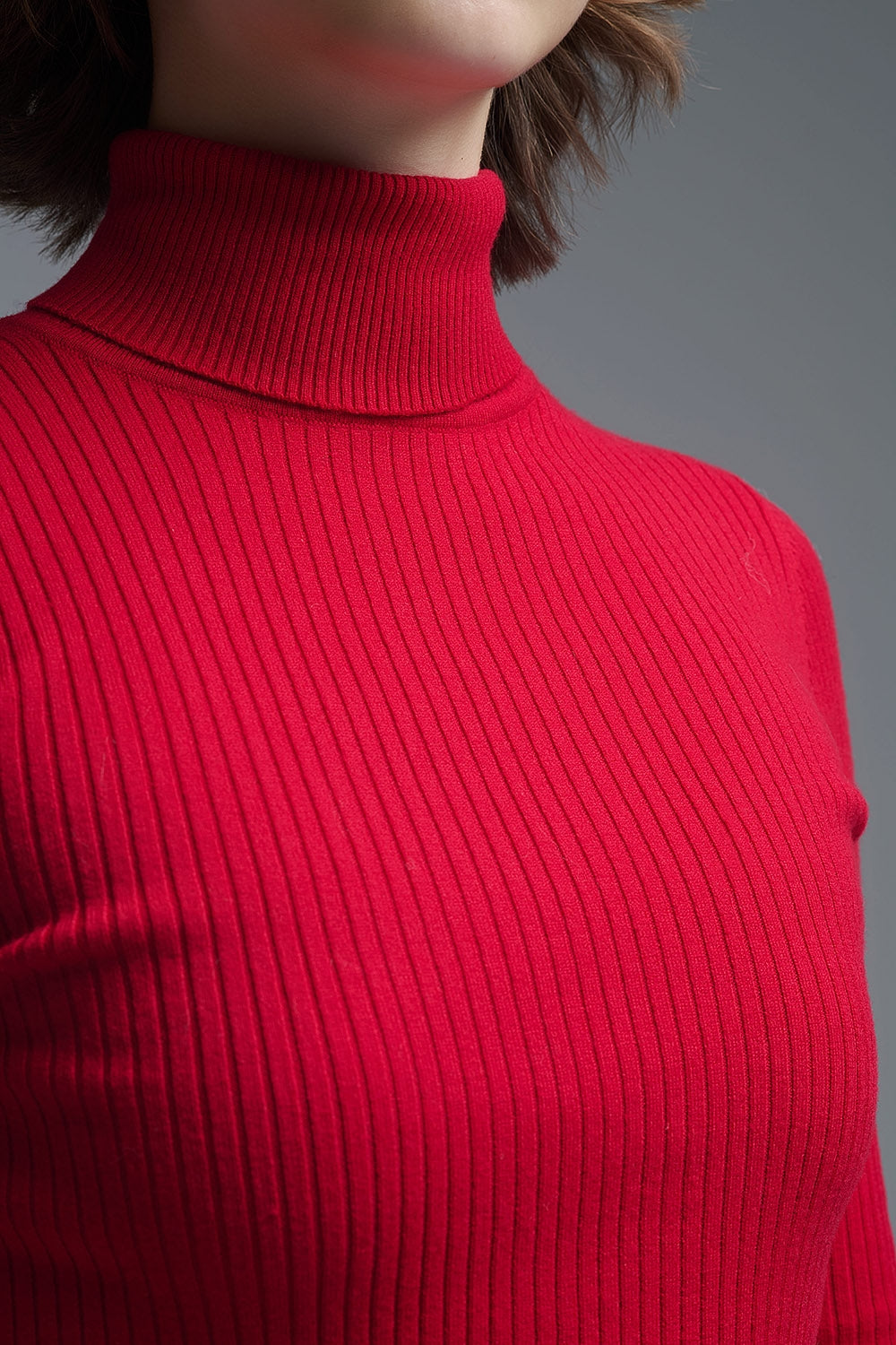 Primer plano del tejido de punto de canalé de un jersey de cuello alto rojo.