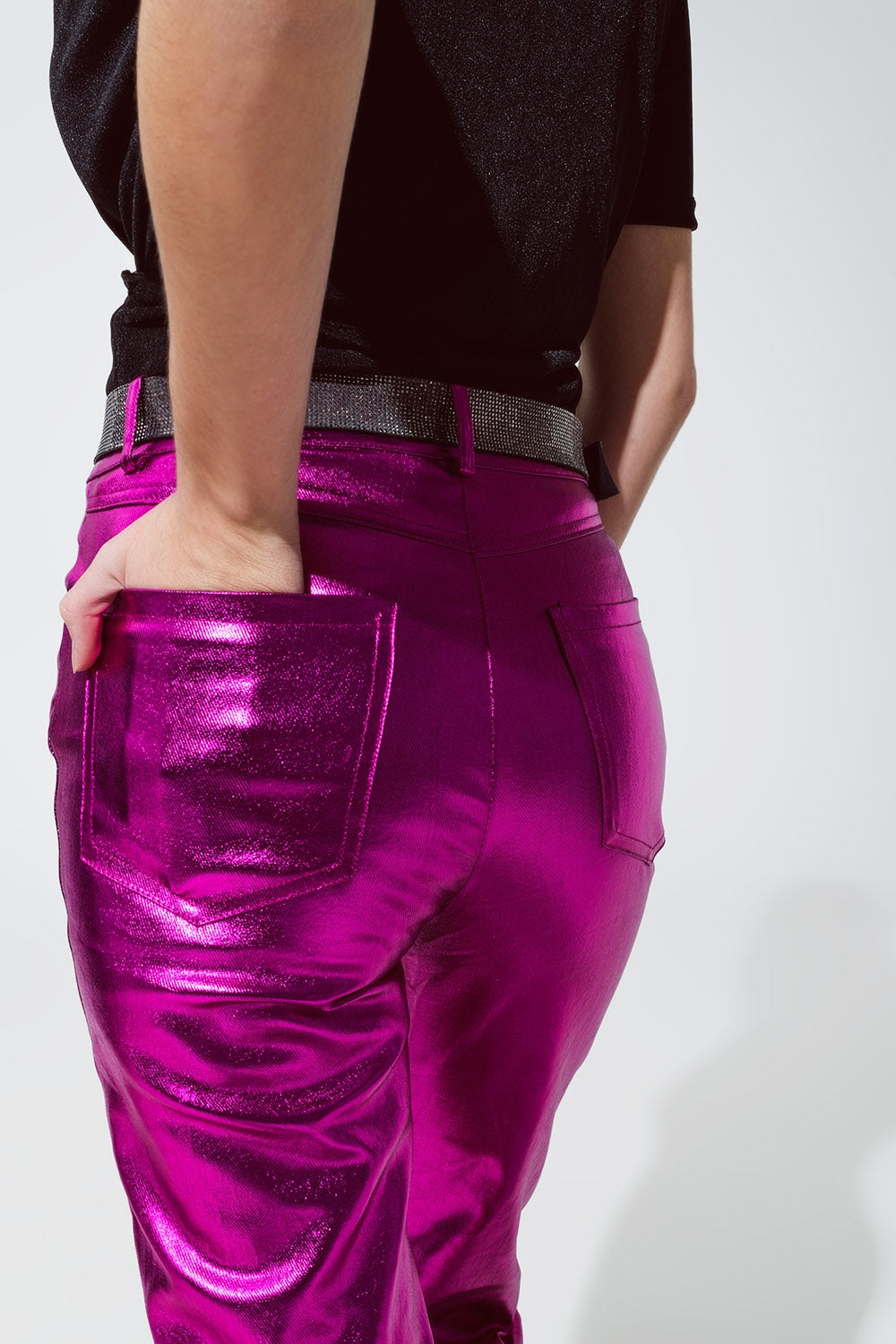 Primer plano del tejido brillante efecto vinilo de un pantalón metalizado en color fucsia.