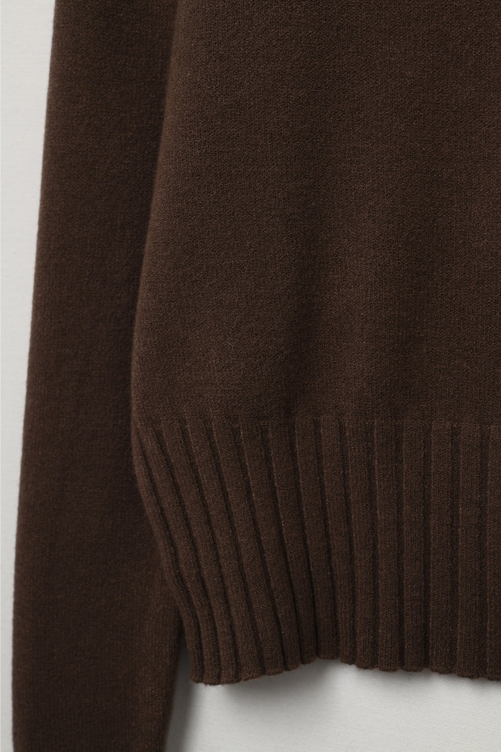 Detalle macro de la textura de punto suave y el acabado de canalé en el bajo de un jersey marrón.