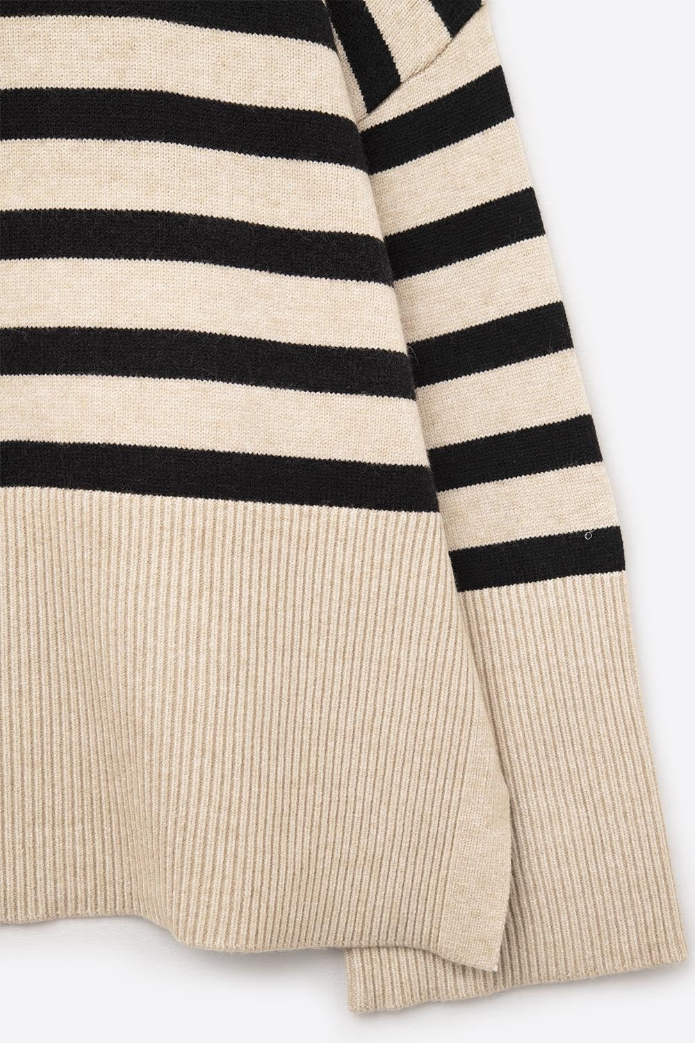 Primer plano del tejido de punto suave de un jersey de rayas beige y negro.