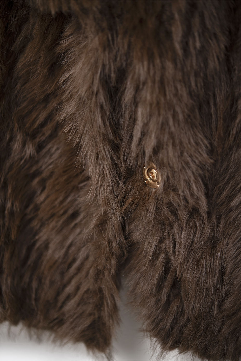 Primer plano de la textura de pelo largo sintético color marrón y detalle del cierre de broche a presión.