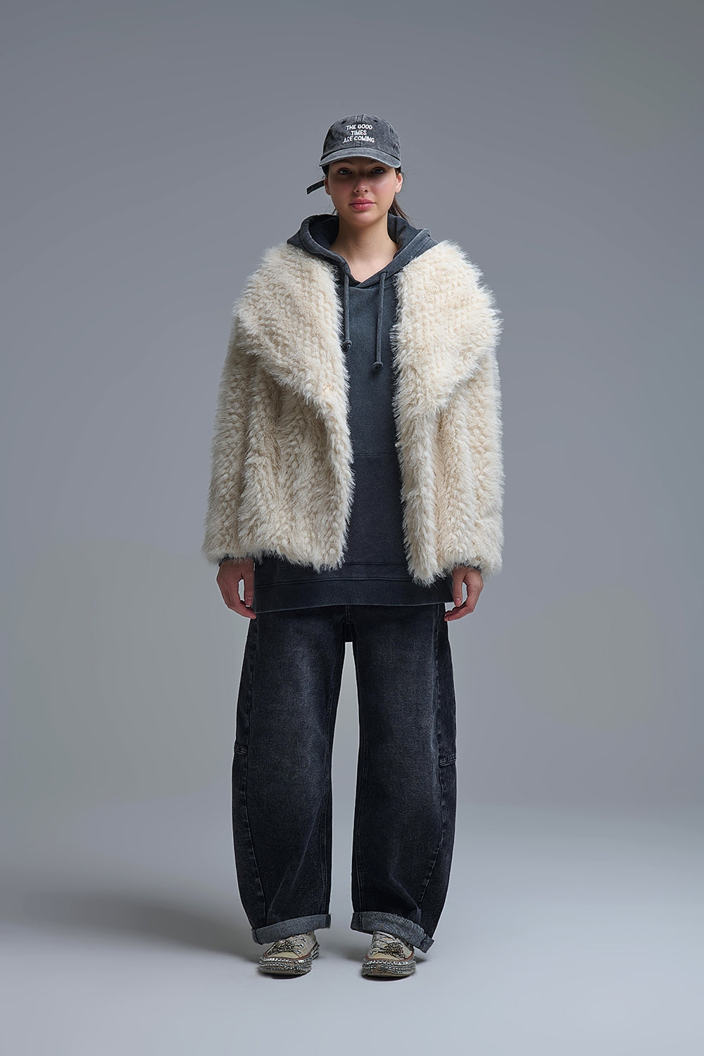 Modelo con chaqueta oversize de pelo sintético "shaggy" en color crudo, sobre una sudadera gris y vaqueros.