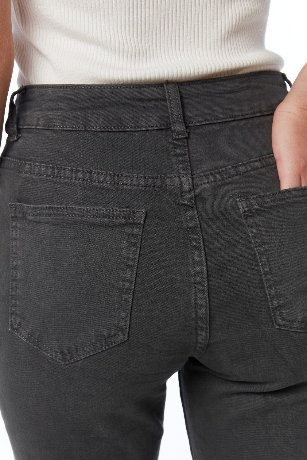 Vista trasera de los bolsillos y el talle alto de un pantalón vaquero ancho en color negro desgastado.