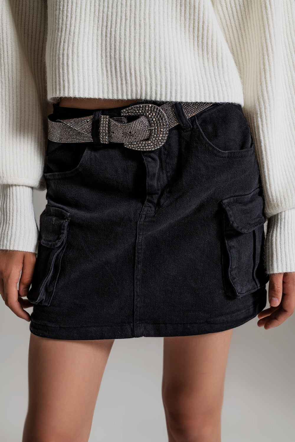 Detalle cinturilla y bolsillos cargo en falda denim negra.